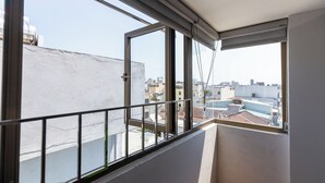Een balkon met een metalen hekwerk, uitzicht op de stad en een gebouw met een witte gevel.