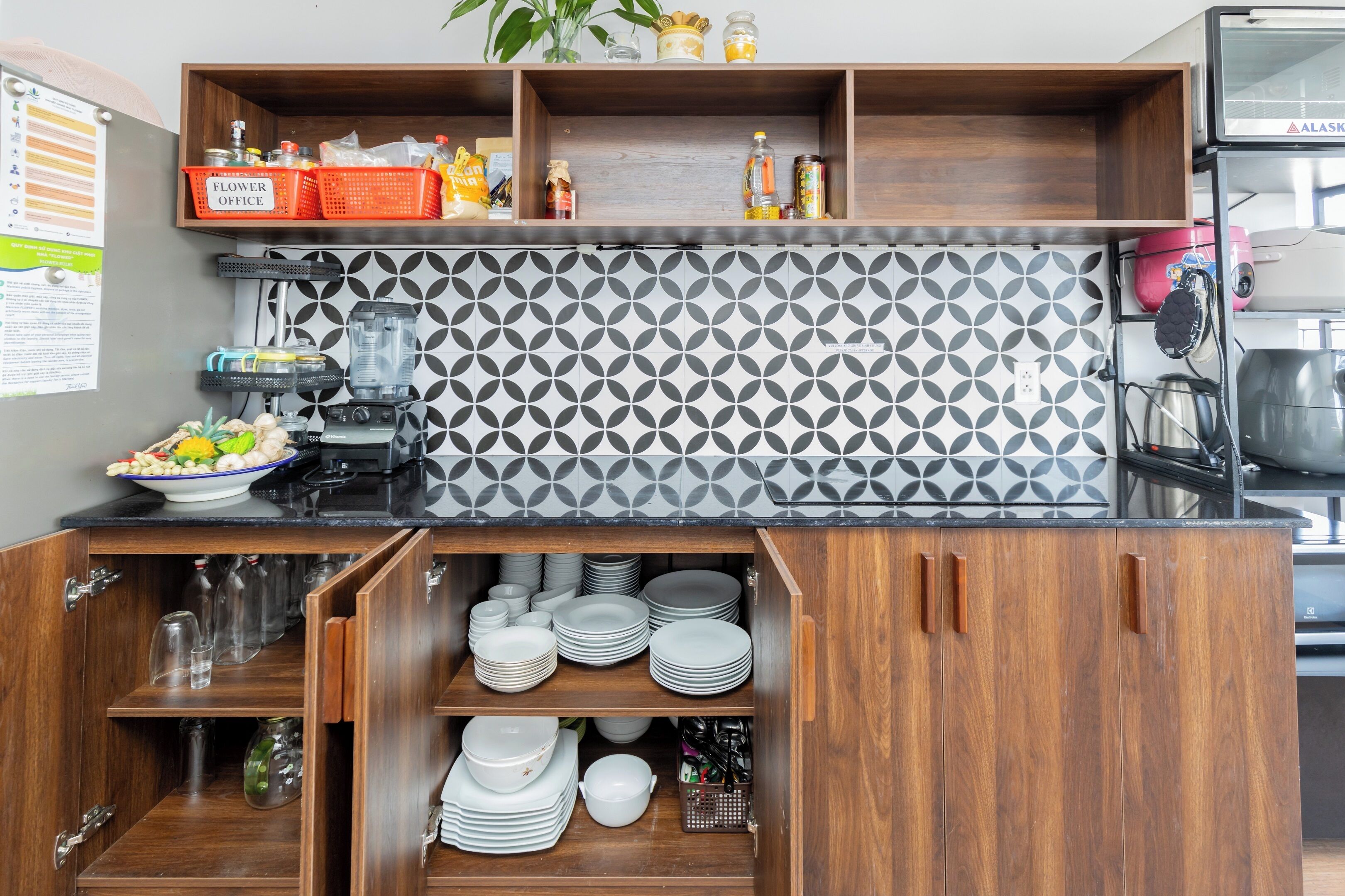A kitchen with wooden cabinets, a black countertop, and a patterned backsplash.
