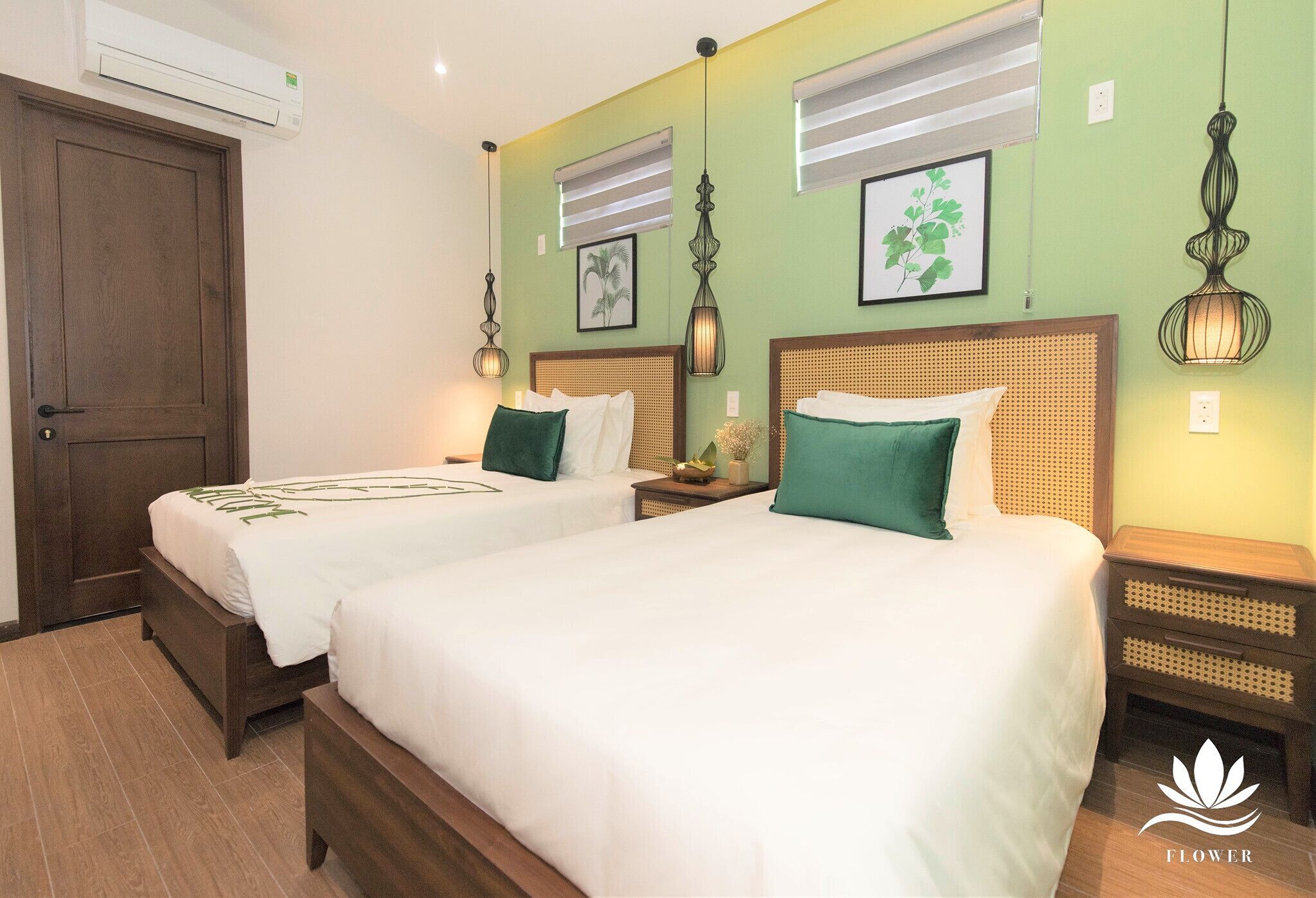 Habitación de hotel con dos camas, una puerta de madera y una pared verde.