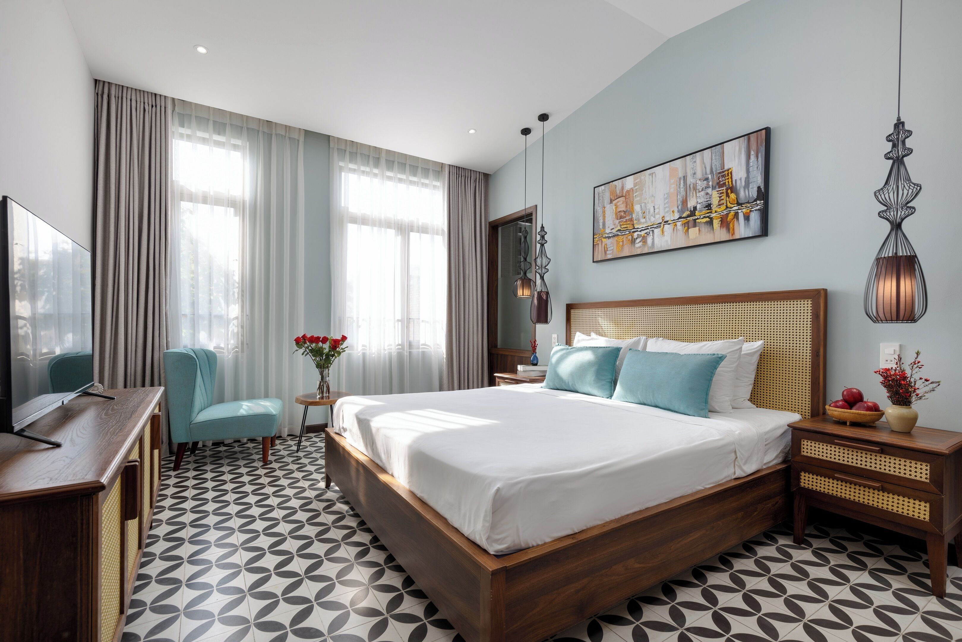 A modern hotel room with a large bed, a TV, a desk, and a chair.