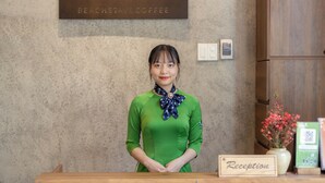 Een receptiebalie met een bordje met de tekst 'Receptie' en een bord erboven met 'Flower Beach Stay & Coffee'.