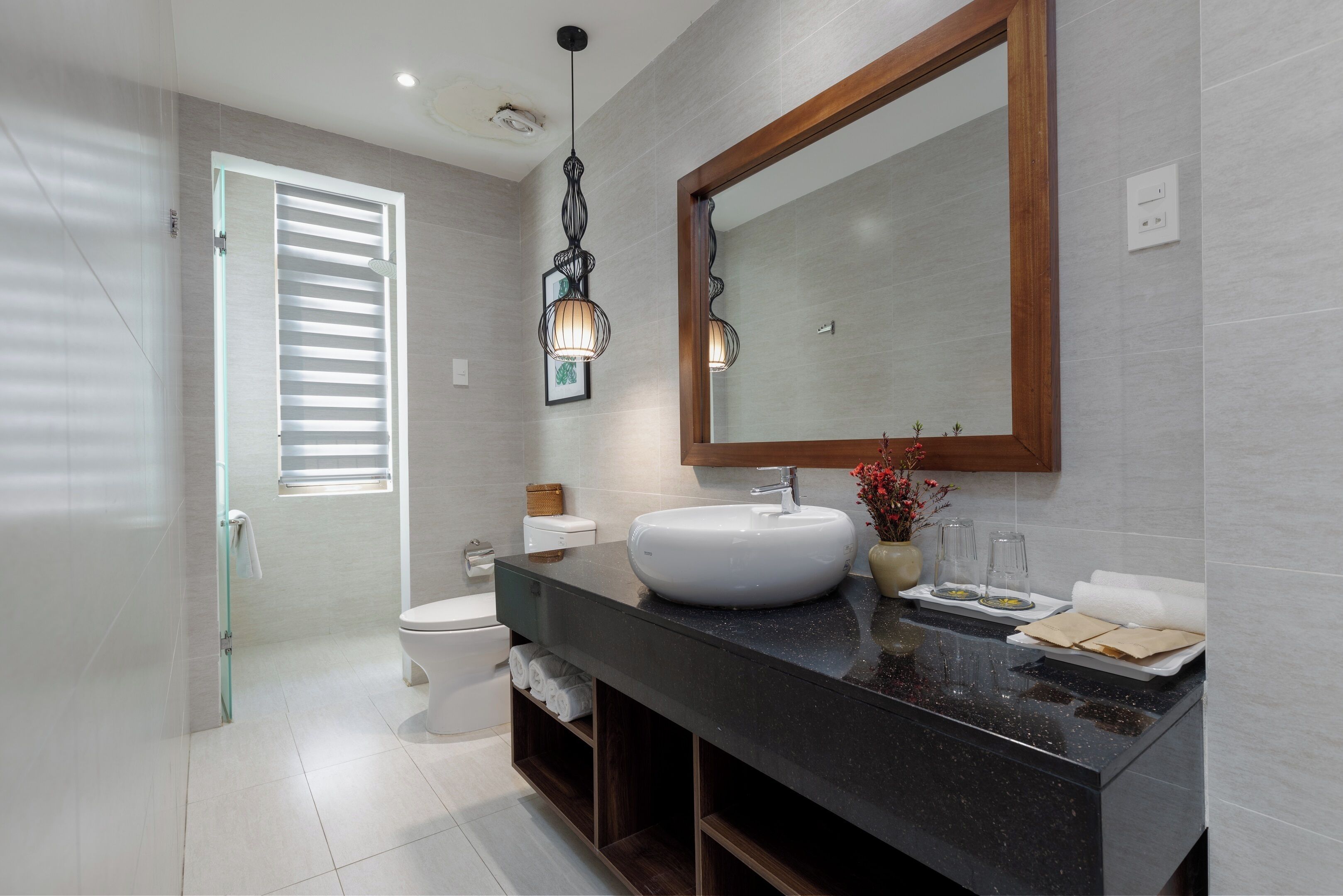 A modern bathroom with a black countertop, white sink, and a large mirror.