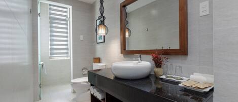 Une salle de bain moderne avec un plan de toilette noir, un lavabo blanc et un grand miroir.