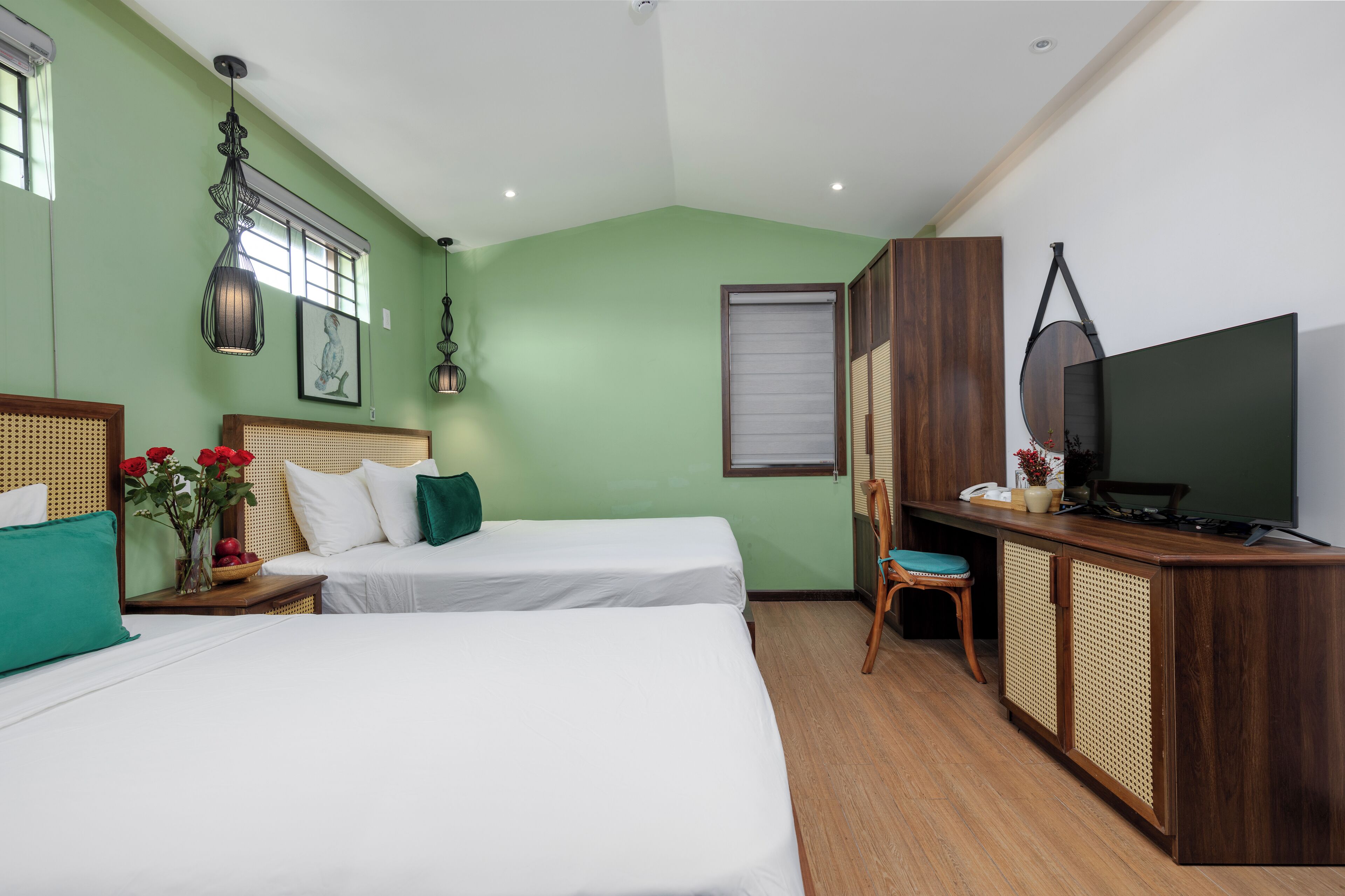 A hotel room with two beds, a desk, a television, and a window with blinds.