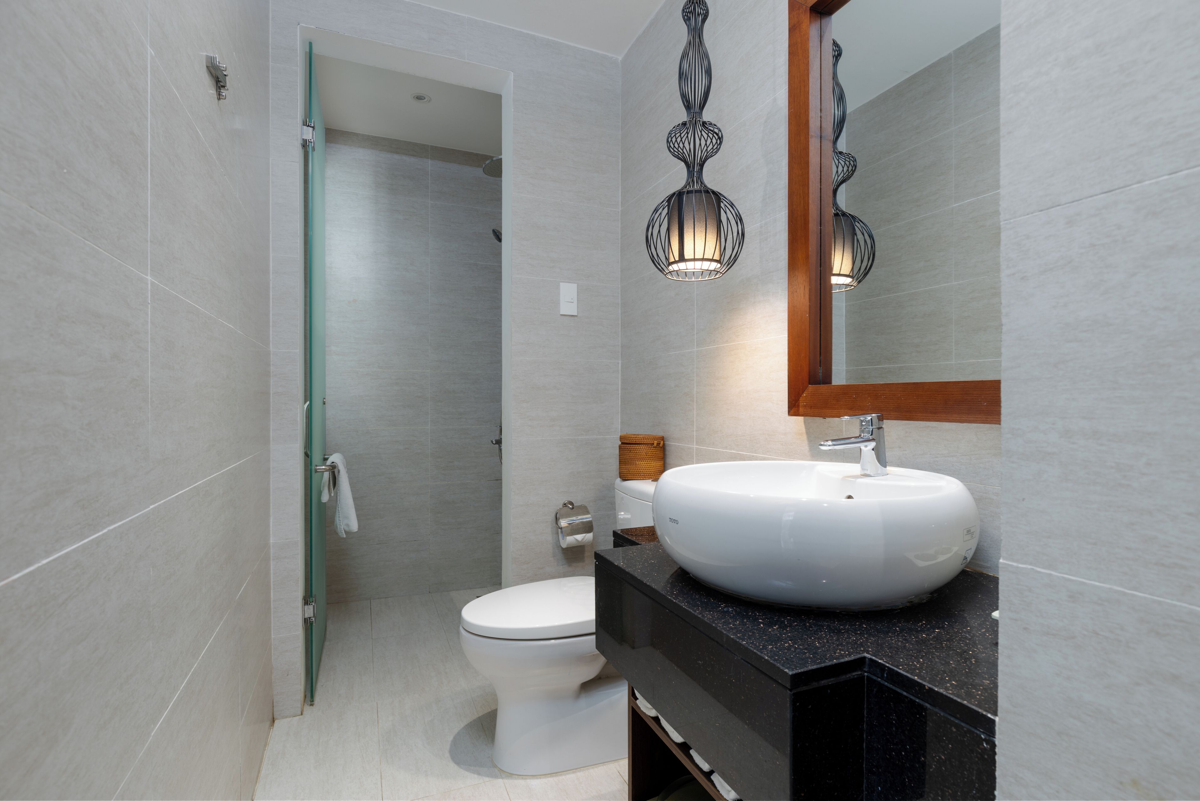 A modern bathroom with a white toilet, a black countertop sink, and a glass shower door.