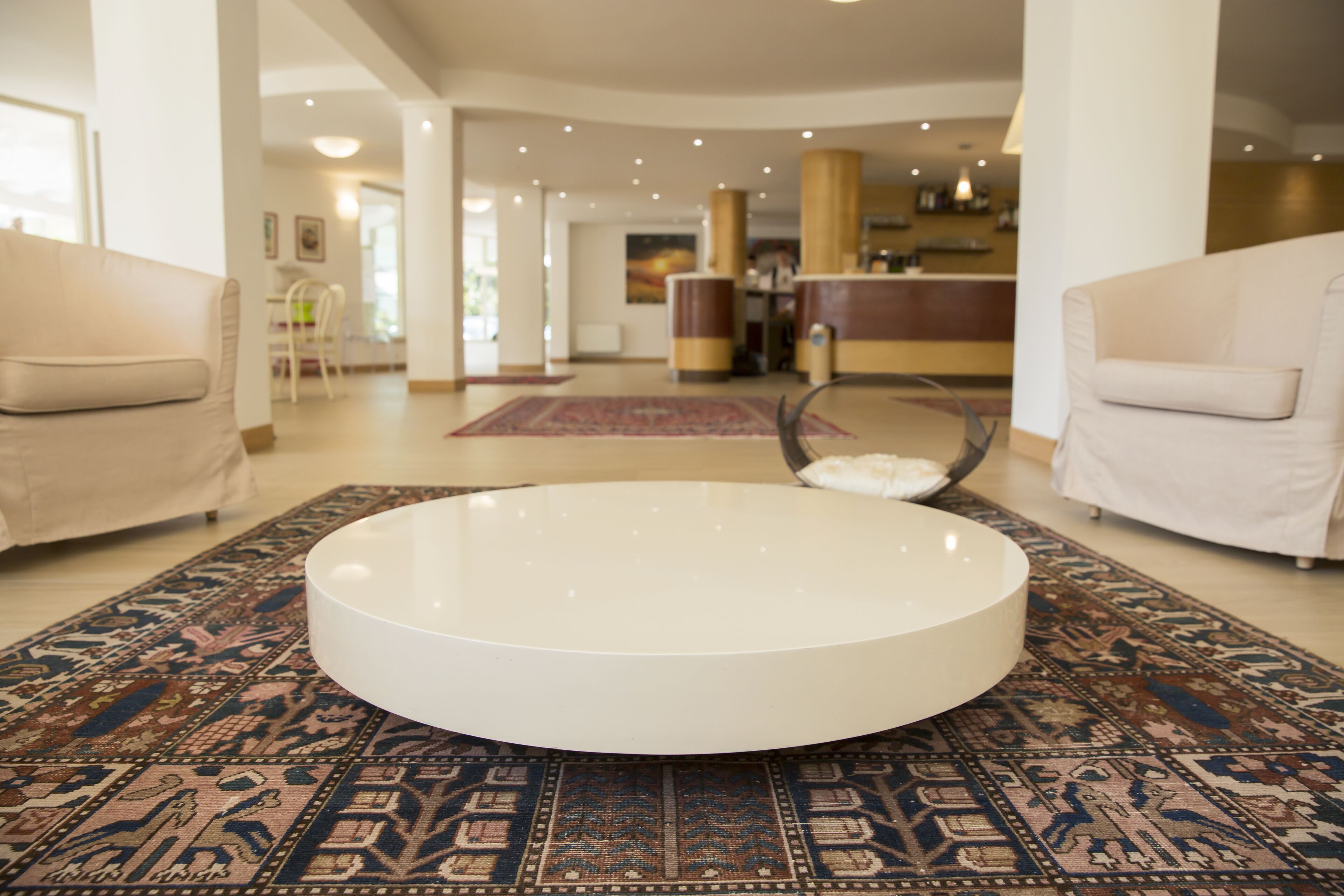 A spacious living area with a round coffee table, two sofas, and a patterned rug.