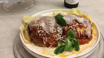 Un plato de pollo a la parmesana con una botella de vino Achelo al fondo.