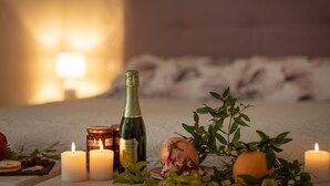 A cozy room with a bed, candles, a bottle of wine, and fresh fruits. - San Michele al Castello (Castiglion Fiorentino)