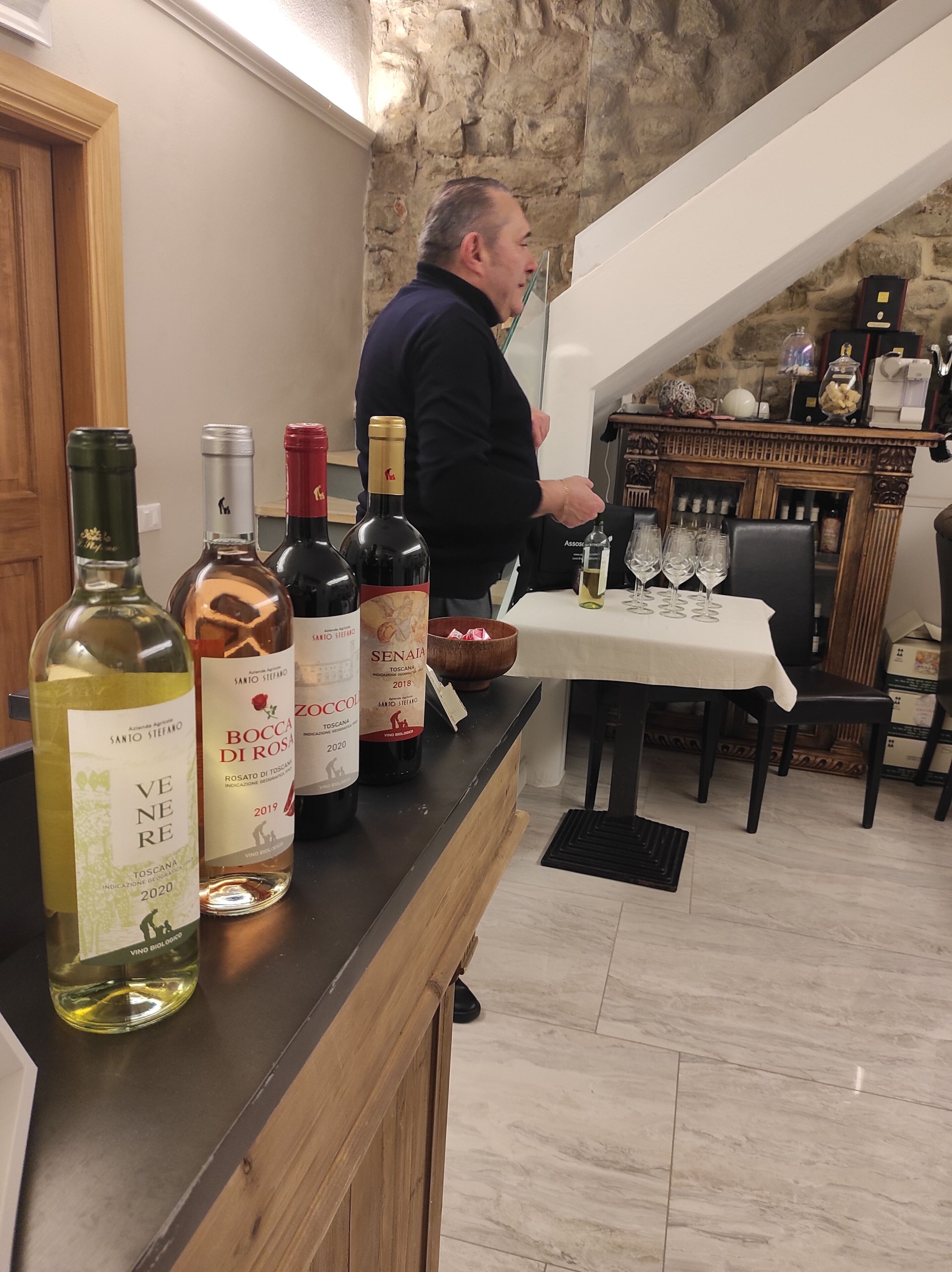 A bar area with wine bottles and glasses on a counter.