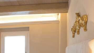 A neatly made bed with white linens, a bedside lamp, and a decorative wall piece.