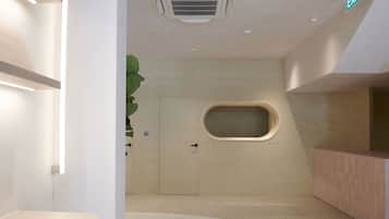 A modern bathroom with a large bathtub, a wooden vanity, and a green plant.