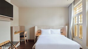 A hotel room with a bed, a desk, a chair, and a TV. - KINN Studios (Singapore)