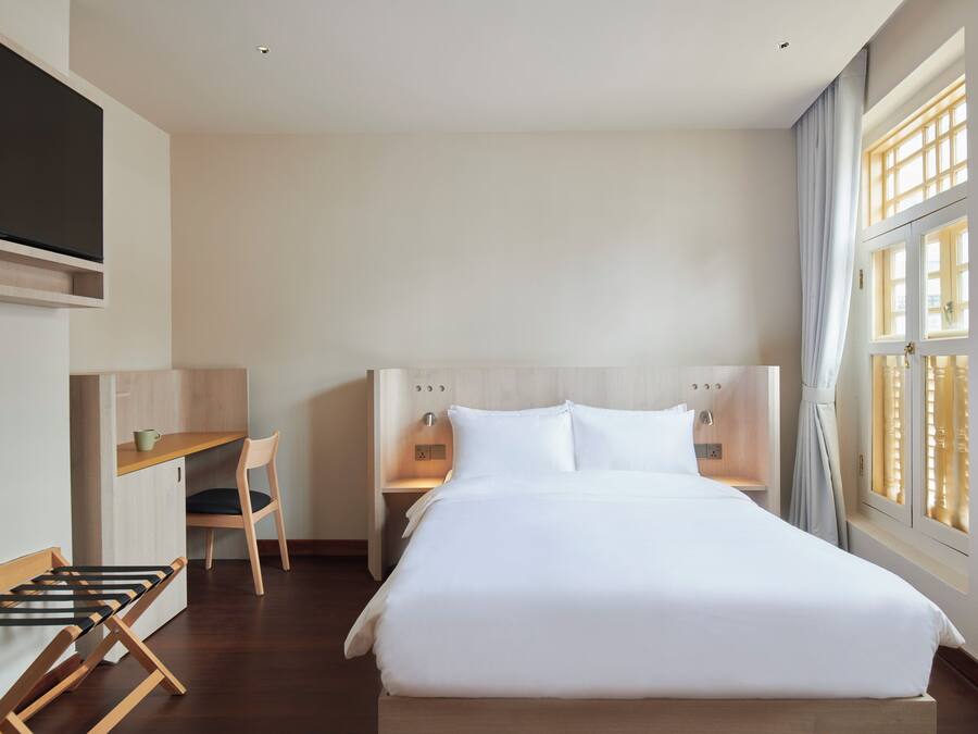 Una habitación de hotel con una cama, un escritorio, una silla y un televisor.