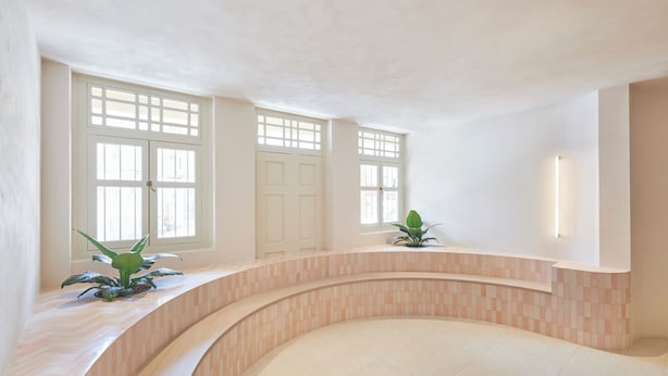 A spacious indoor area with a curved wall, large windows, and a potted plant. - KINN Studios (Singapore)