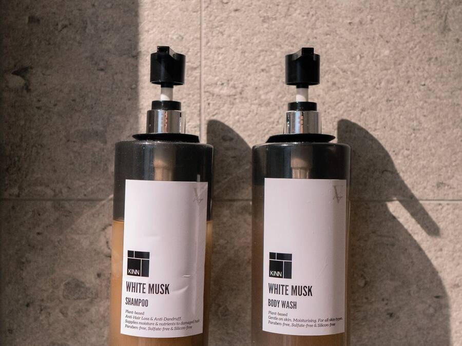 Dos botellas de crema corporal White Musk sobre una superficie texturizada.