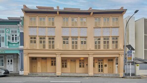 A multi-story building with a symmetrical facade, large windows, and a central entrance. - KINN Studios (Singapore)