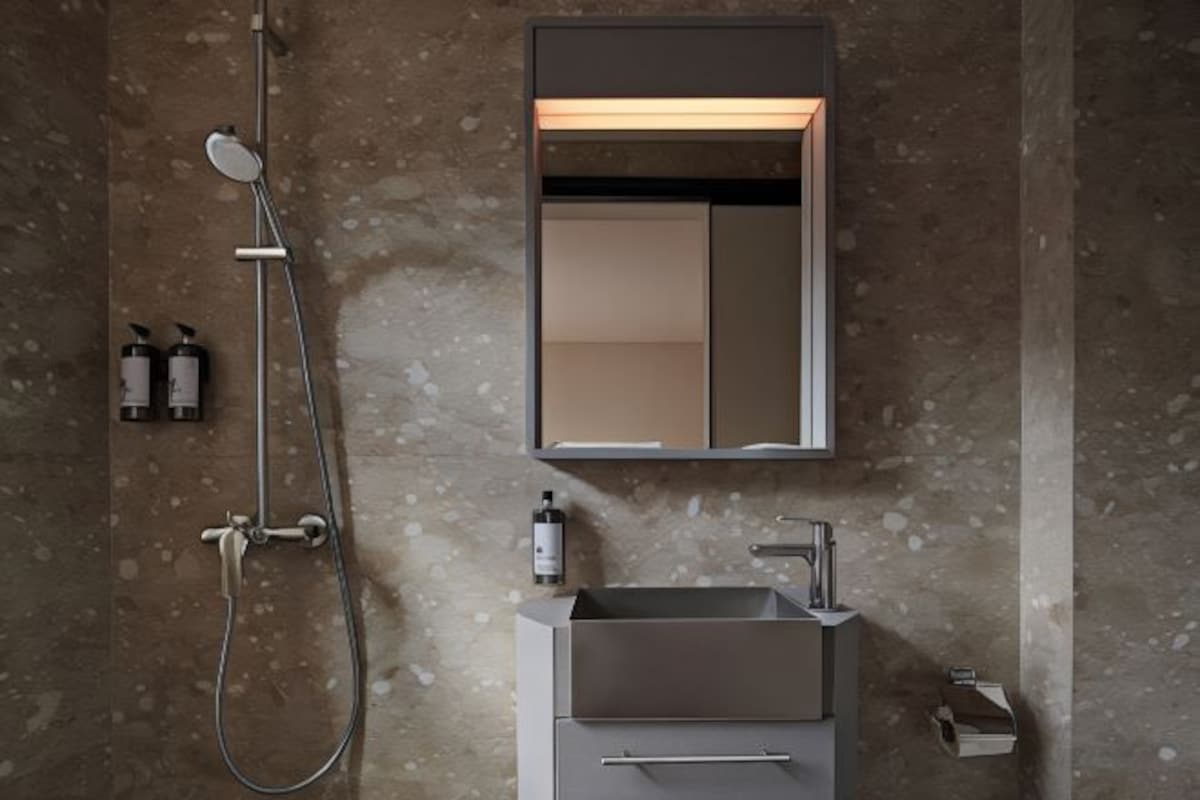 A modern bathroom with a built-in sink, a handheld showerhead, and a mirror.