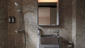 A bathroom with a shower, a sink, and a mirror. - KINN Studios (Singapore)