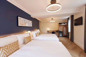A hotel room with two beds, a flat-screen TV, a mirror, a desk, and a wardrobe. - Thistle London Park Lane (London)