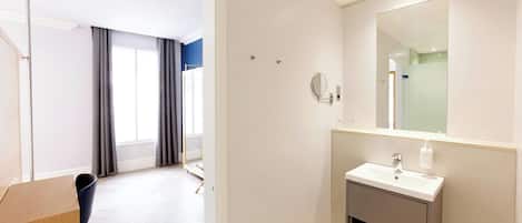 Ein modernes Badezimmer mit Waschbecken, Spiegel und Duschbereich.