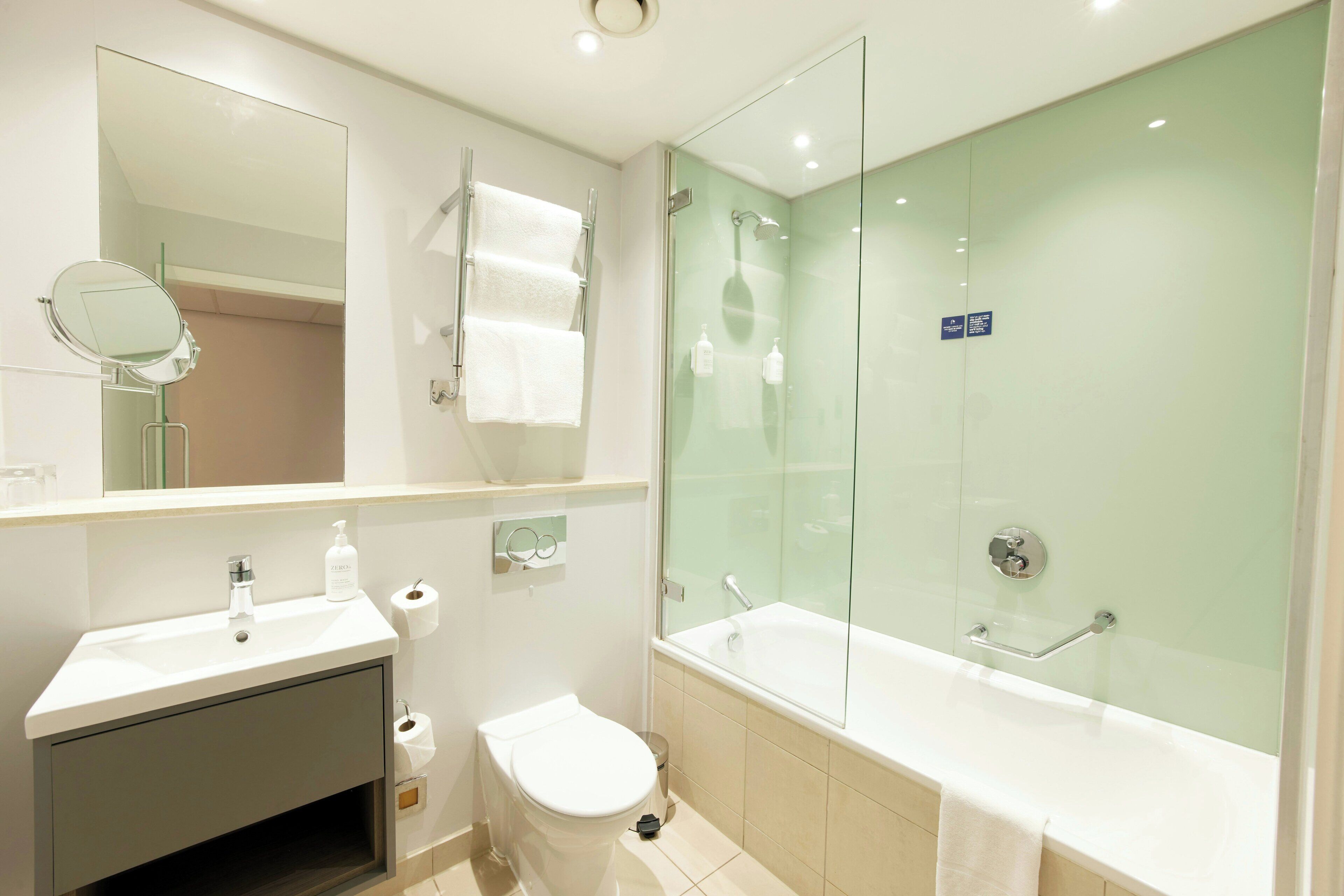A modern bathroom with a glass-enclosed shower, a white sink, and a toilet.