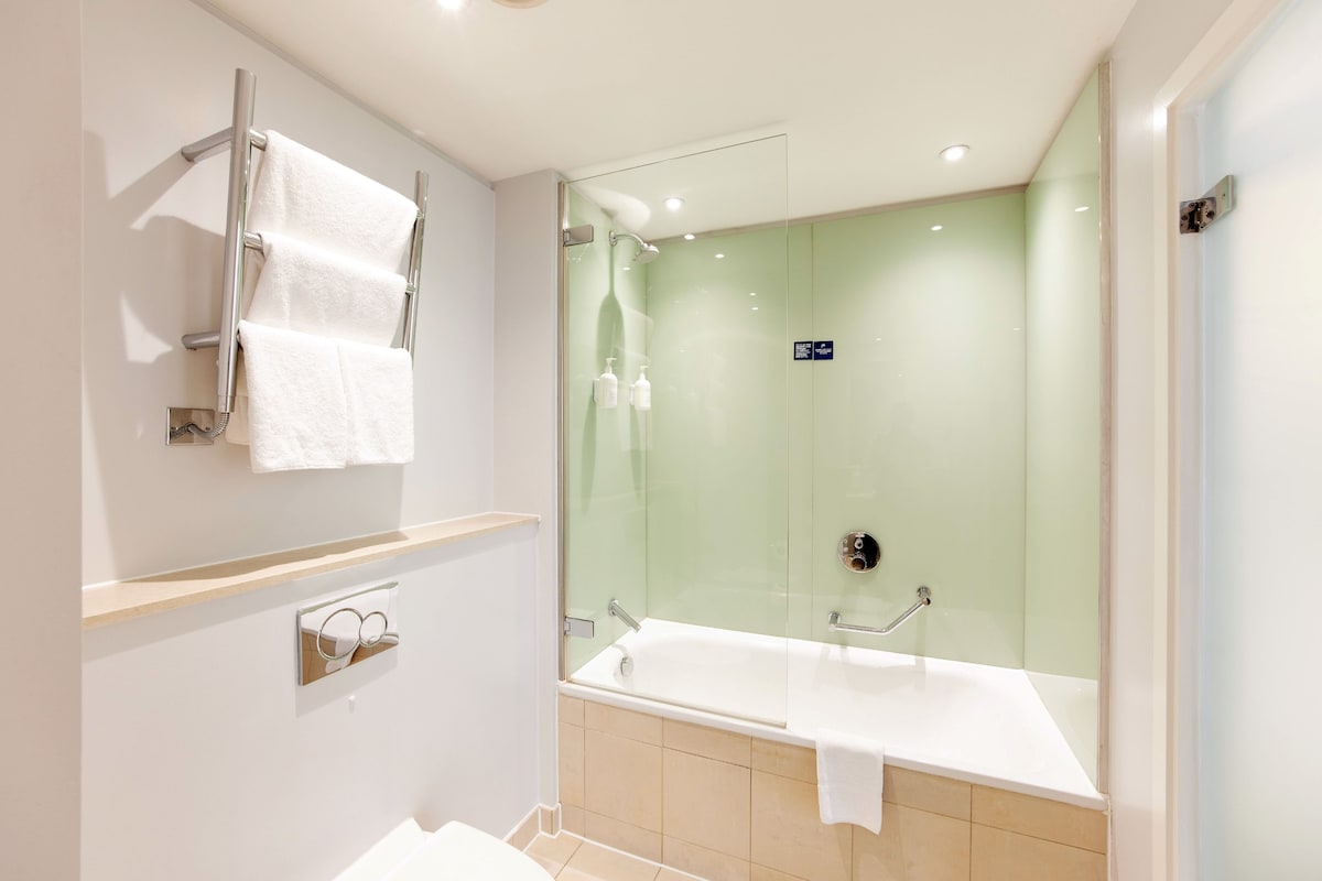 A modern bathroom with a glass-enclosed shower, a bathtub, and a towel rack.