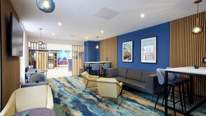 A modern lounge area with a sofa, chairs, a table, and a bar area. - Thistle London Park Lane (London)