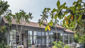 Et moderne hus med en glasfacade, en stenterrasse og en swimmingpool.