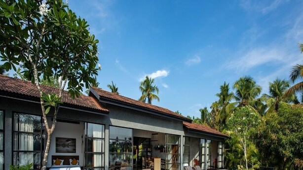 Et moderne hus med swimmingpool, store vinduer og en terrasse med liggestole.