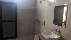 A bathroom with a shower, a sink, a mirror, and a door. - Hotel Moon Rise (Srinagar)