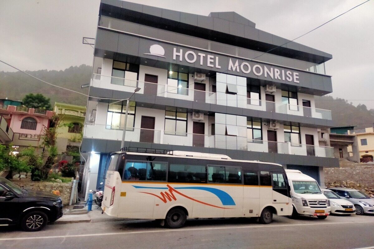 Un hôtel appelé « HOTEL MOONRISE », doté d’une architecture moderne, avec de nombreux étages et de grandes fenêtres.