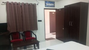 A hotel room with a bed, a desk with a chair, a wardrobe, and a door leading to another room. - Hotel Moon Rise (Srinagar)