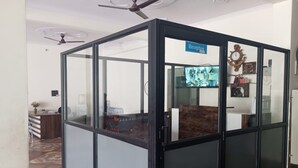 A reception area with a glass partition, a ceiling fan, and a clock on the wall. - Hotel Moon Rise (Srinagar)