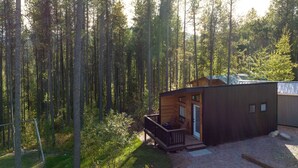 Une cabane dans une forêt, dotée d’une terrasse et d’un espace extérieur couvert.