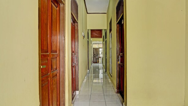 A long, narrow hallway with wooden doors on both sides and a tiled floor. - Hotel O Firza Homestay (Palembang)