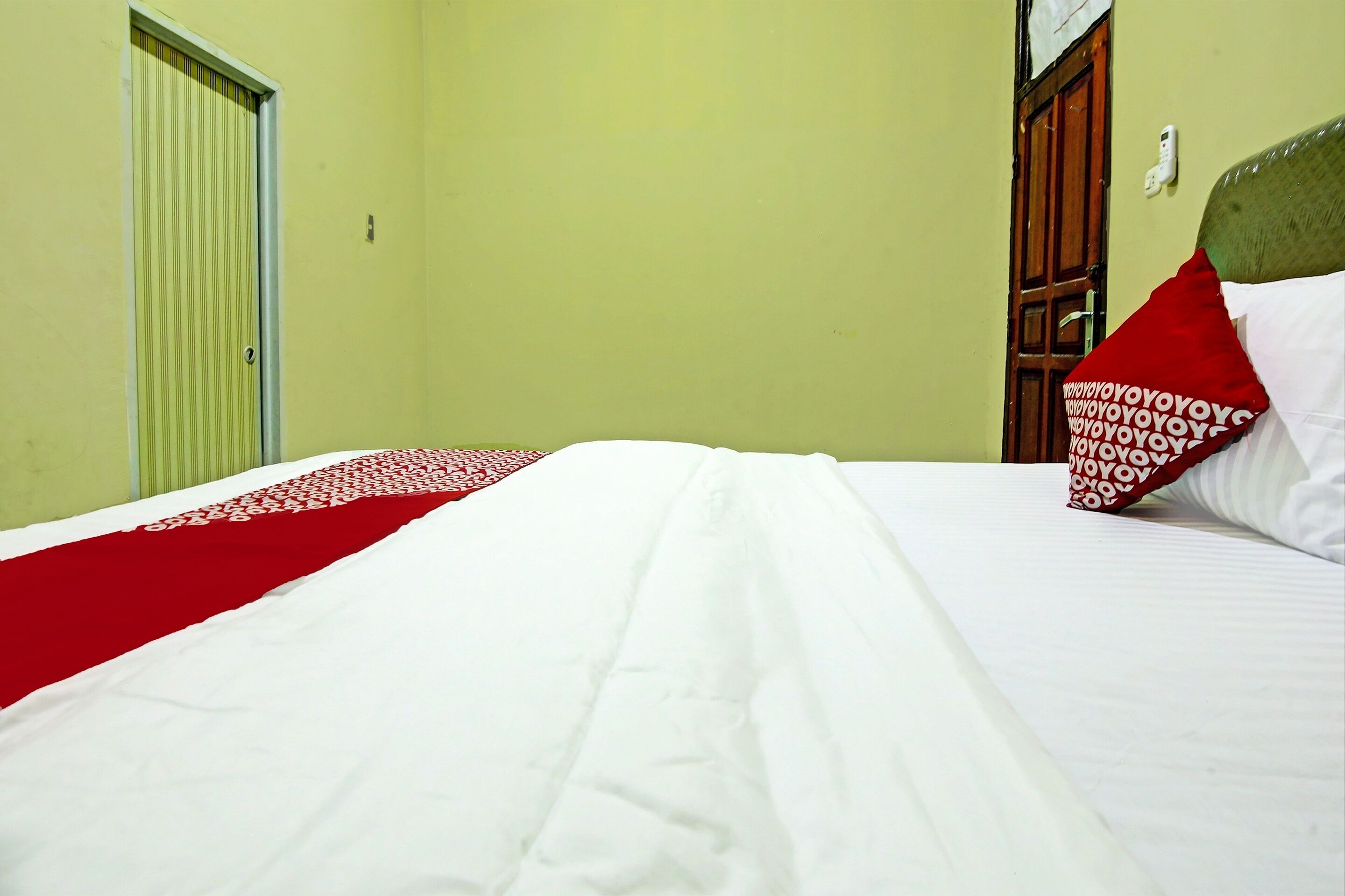 A hotel room with a bed, a door, and a wall socket.