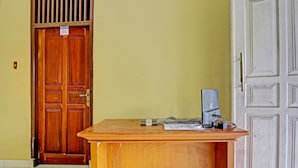 A wooden desk with a computer, papers, and a mobile phone. - Hotel O Firza Homestay (Palembang)