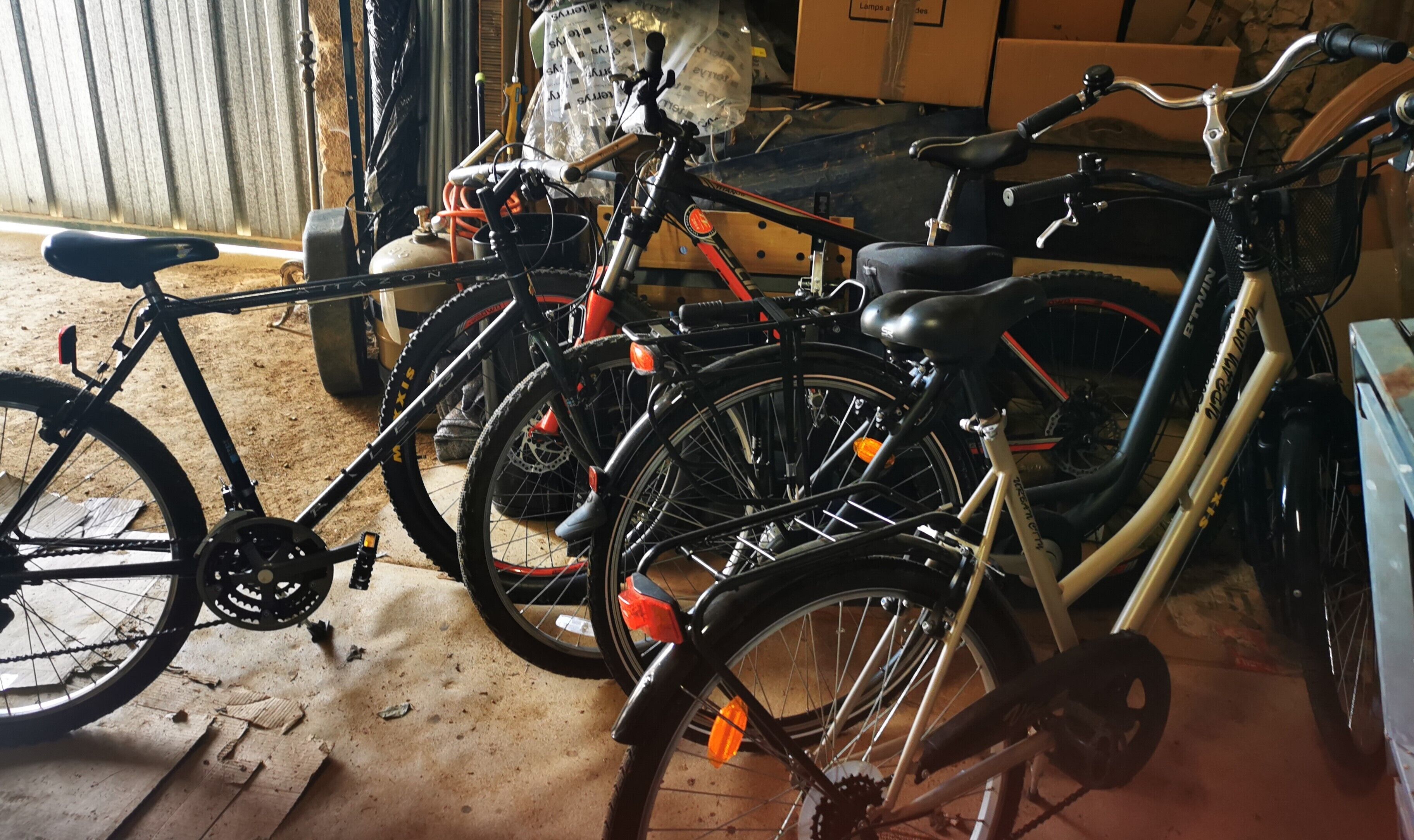 Bicycles parked indoors with a concrete floor and wooden planks.