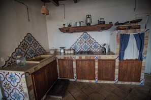 Une cuisine avec des meubles en bois, un dosseret carrelé et un luminaire suspendu.