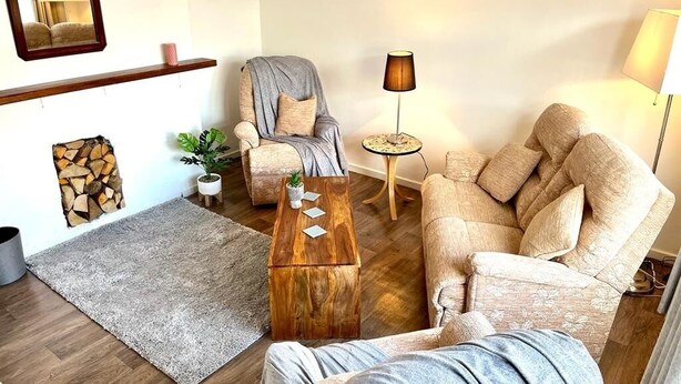 A living room with a grey sofa, a wooden coffee table, a small side table, and a lamp. - Spacious Family Home (Manchester)