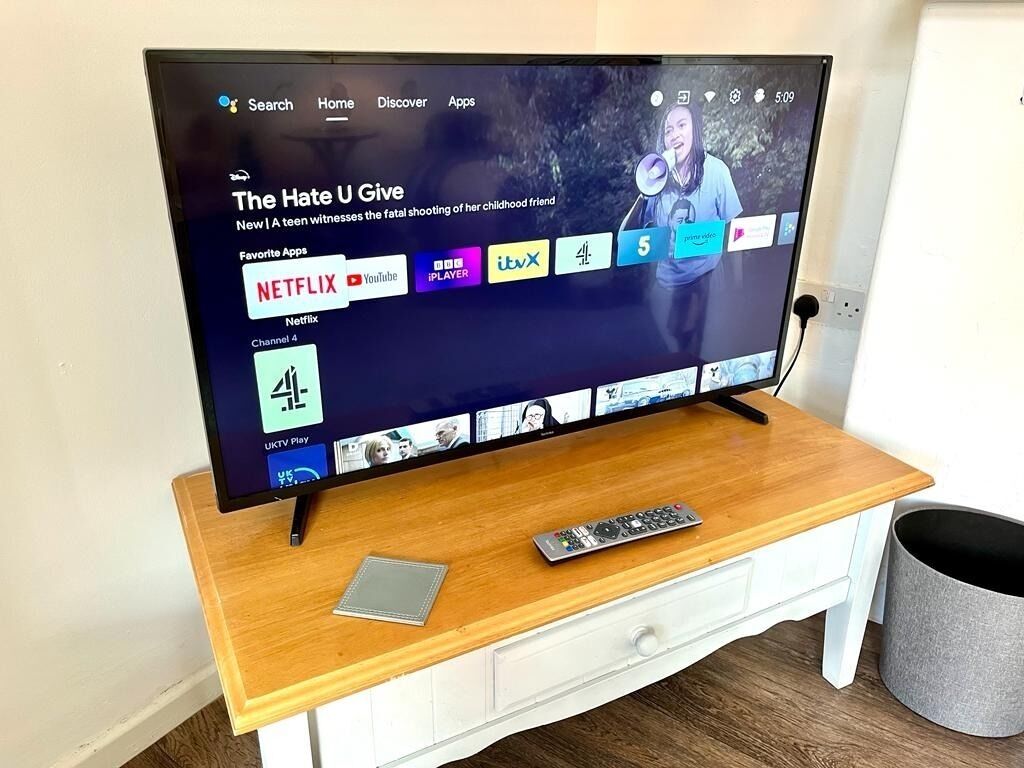 A television on a wooden stand with a remote control beside it.