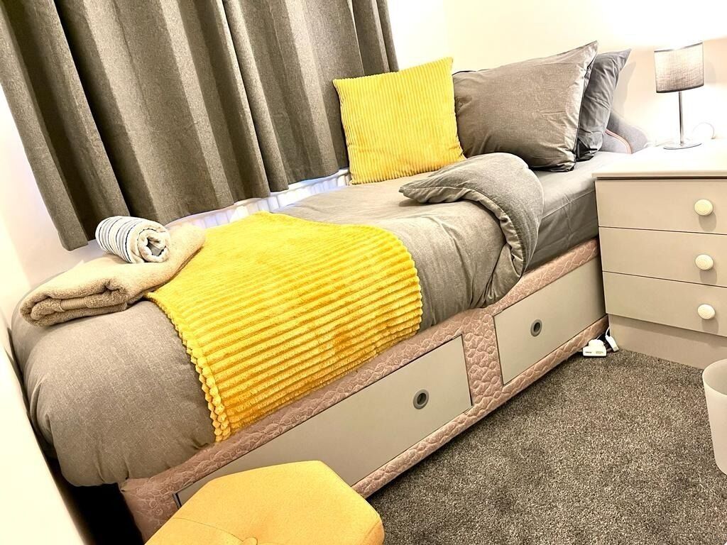 Un lit avec une tête de lit, une table de chevet et une lampe.