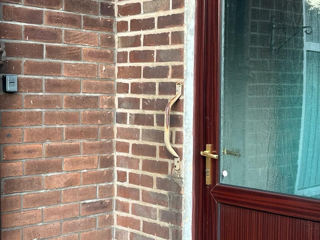En mur av tegelstenar med ett handtag av metall och en dörr av glas.