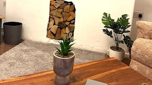 A living room with a stone wall feature, a wooden coffee table, and two potted plants. - Spacious Family Home (Manchester)