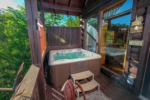 A wooden deck with a hot tub, a wooden chair, and a glass door leading to a garden.