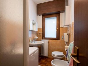 Bathroom features a sink, toilet, and bidet, with a window above the toilet and a towel rack.