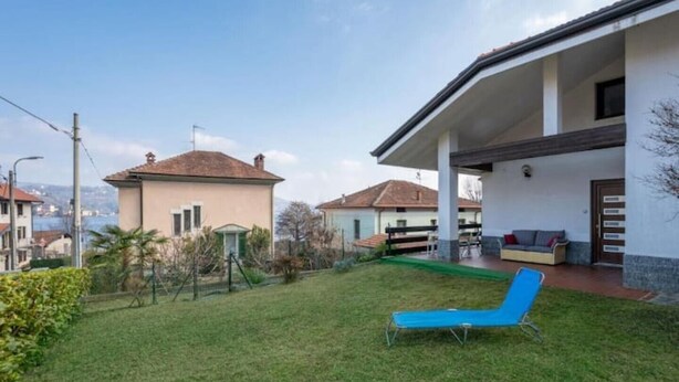 A residential property with a covered patio, a lawn, and a blue lounge chair.