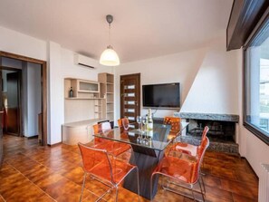 Enjoy meals in this stylish dining area with a glass table and comfortable seating for four, featuring a TV above the fireplace and a large window with city views.