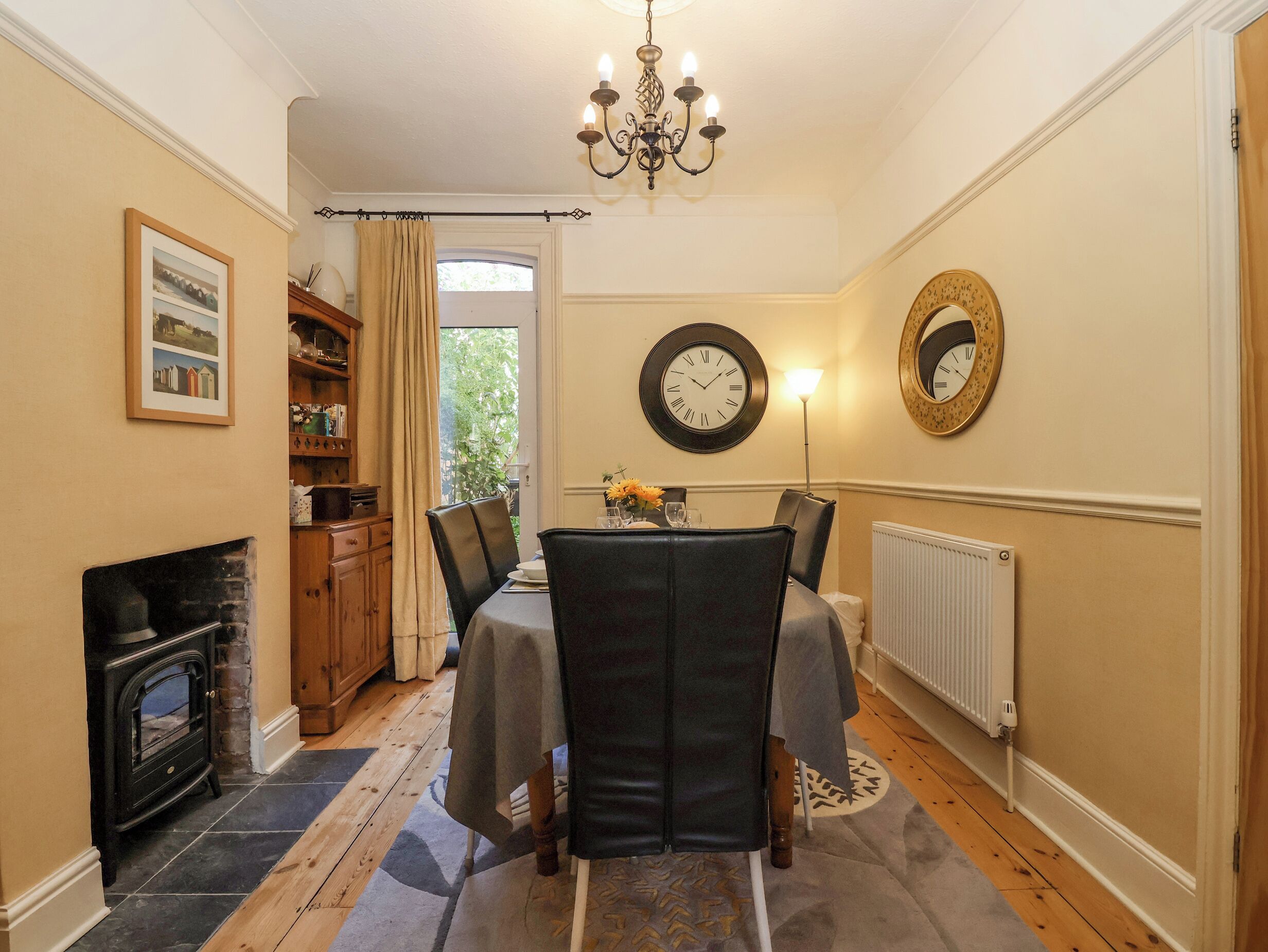 A dining room with a table set for four, a fireplace, and a large window with curtains.