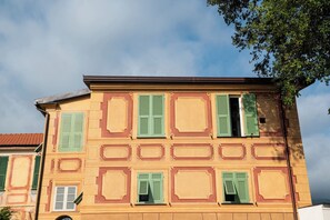 Un bâtiment doté de nombreuses fenêtres et de volets verts, avec une façade symétrique agrémentée de moulures décoratives.